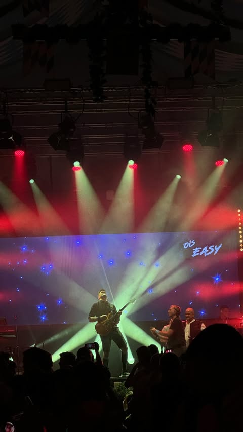 OisEasy live: Musiker vor einer LED-Wand mit roten und warmweißen Lichtstrahlen
